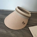 Detailed close-up of straw woven texture and chic bow accessory on sun visor hat - Pink