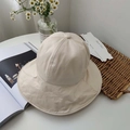 Overhead view of a foldable beige sun hat on a table with lifestyle decorative props - Beige