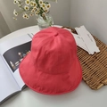 Detailed top view of a foldable coral pink sun hat on a white table with lifestyle props - Watermelon red