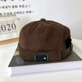 Detail of dark brown corduroy texture and adjustable metal buckle on a retro docker cap - Coffee