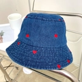 Dettaglio cappello bucket in denim blu con ricami a cuore rosso su supporto silver - Regolabile / Blu scuro