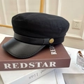 Detailansicht der Kapitänsmütze mit Lederschirm und goldener Vintage-Taste auf Büchern - 56-58cm (Verstellbar) / Schwarz