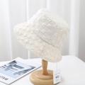 Detailed texture of a white seersucker bucket hat on a wooden stand with tags - 55-58cm / Beige
