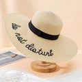 Detail of beige straw hat featuring black do not disturb embroidery on wide brim - 55-59CM / Beige