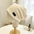 Detail of beige waffle knit beanie with black label on a fabric mannequin head - 56-58cm / Beige