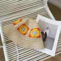 Detail showing colorful granny square patterns on a woven straw bucket sun hat - One Size / Beige