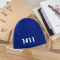 Dettaglio del berretto in maglia blu con ricamo 1011 bianco su tavolo in legno - 55-58cm / Blu Zaffiro