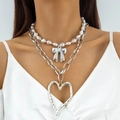 Close-up of layered necklace featuring faux pearls, bow charm, and large hammered heart pendant - Silver (Layered Pearl Bowknot Heart Pendant)
