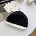 Strickmütze mit Schwarz-Weiß-Farbblock-Design und Umschlag auf kreativem Schreibtisch - Schwarz und Weiß