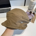 Brown pleated bucket hat with silver metal detail shown in a minimalist studio setting - 56-58cm / Camel