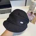 Women's black textured bucket hat with silver oval metal logo in a lifestyle desk setting - 56-58cm / Black