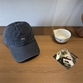 Dark gray washed canvas baseball cap featuring white Lucy embroidery on a wooden table - Gray