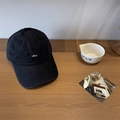 Black baseball cap with white Lucy embroidery on twill cotton, displayed on a wooden table - Black