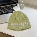 Light green knit beanie with Adventure embroidery on a clean desk with accessories - 56-58cm / Fruit Green
