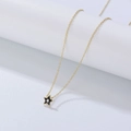 Detail van een gouden ketting met een zwarte sterhanger en een kleine zirkoonsteen - 925 zilver / Zwart