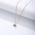 Macro shot of rose gold angel wing pendant with blue heart zircon on white stand - 925 Silver / Rose Gold