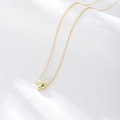 Dettaglio di un ciondolo a cuore 3D dorato su una catena sottile sopra seta bianca - Argento 925 / Oro