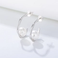 Vista macro di orecchini a C in argento S925 con perle bianche e lucenti - Argento 925 / Bianco