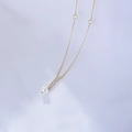 Dettaglio macro del ciondolo a nappa dorata con zirconi incastonati e perla bianca tonda - Argento 925 / Oro
