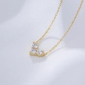Vista macro del collar en V dorado con tres piedras de circonita de corte redondo - Plata 925 / Amarillo