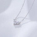 Vista macro de un collar con colgante de corazón de plata con tres circonitas en tela - Plata 925 / Blanco