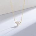 Gros plan du collier pendentif coeur doré avec trois zircons sur socle blanc épuré - Argent 925 / Or