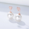 Dettaglio di orecchini a cuore in oro rosa con zirconi e grandi perle bianche tonde - Argento 925 / Oro rosa