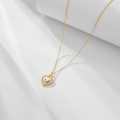 Nahaufnahme eines goldenen Herzanhängers mit Zirkonia auf weißem Display - 925er Silber / Gold