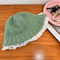Pale green knitted bucket hat with white lace trim shown on a wooden background - 56-58cm / Green