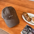 Minimalist deep brown canvas baseball cap with white 'me' embroidery on wooden desk - Coffee