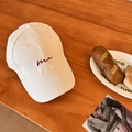 Off-white cotton baseball cap featuring red 'me' embroidery on a wooden table - Off-white