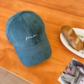 Corduroy baseball cap in deep green featuring white "me" embroidery on wood background - Army Green