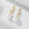 Detailed macro view of S925 silver pearl earrings with zircons on white pedestal - 925 Silver / Yellow