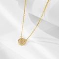 Nahaufnahme der vergoldeten Silberkette mit einem runden Zirkonia-Anhänger auf weißem Sockel - 925er Silber / Gold