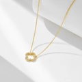 Close-up of a hollow clover pendant necklace in gold with micro-paved sparkling crystals - 925 Silver / Gold