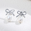 Elegant S925 silver bow stud earrings with natural freshwater pearls on stone texture - 925 Silver / Silver