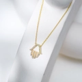 Detail of gold Hamsa hand necklace with white zircons on minimalist stone pedestal - 925 Silver / Gold