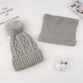 Detail of light gray cable knit beanie with fluffy pompom and matching neck warmer scarf - Hat And Scarf Set / Gray