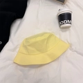 Cappello a secchiello in cotone giallo tenue con tesa cucita su sfondo di lenzuola bianche - 56-60cm / Giallo
