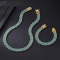 Dettaglio del set catena cubana dorata con strass azzurri su sfondo nero testurizzato - Collana 45cm + Bracciale 20cm / Oro Strass Blu (Set Collana e Bracciale)