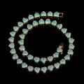 Golden heart tennis necklace with pavé blue crystals on a reflective black background - Gold Blue