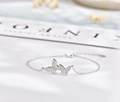 Detalle de pulsera mariposa de plata 925 con circonitas pavé sobre una tela azul suave - Plata 925 / Oro Blanco