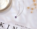 Detalle del collar de plata S925 con piedra redonda púrpura sobre tela de satén blanco - Un Quilate / Púrpura de Ensueño