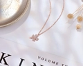 Dettaglio collana a quadrifoglio in oro rosa con pietre bianche lucide su seta morbida - Oro rosa