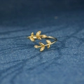 Eleganter S925 Silberring in Blattform mit Zirkonia-Steinen auf dunkelblauem Textilgrund - Einstellbar Offen / Gold