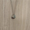 Détail du collier avec pendentif cœur en argent au fini poli sur un fond en bois naturel - Style Coeur Simple / Argenté