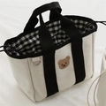 Detail of canvas bag showing bear embroidery, checkered lining, and drawstring closure - Black