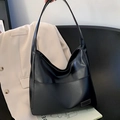 Black leather hobo shoulder bag with a glossy finish and long strap on a chair - Black