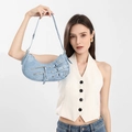 Dettaglio della borsa hobo in denim azzurro con cerniere e fibbie in metallo in stile biker - Blu
