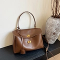 Bruine lederen shopper met gouden draaisluiting en schouderriem op moderne display - Bruin